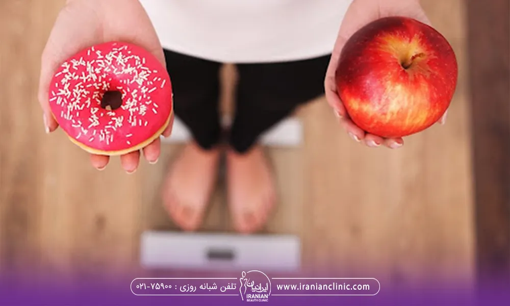 فردی که روی ترازو ایستاده و برای لاغری در حال انتخاب کردن خوراکی است کیک یا سیب