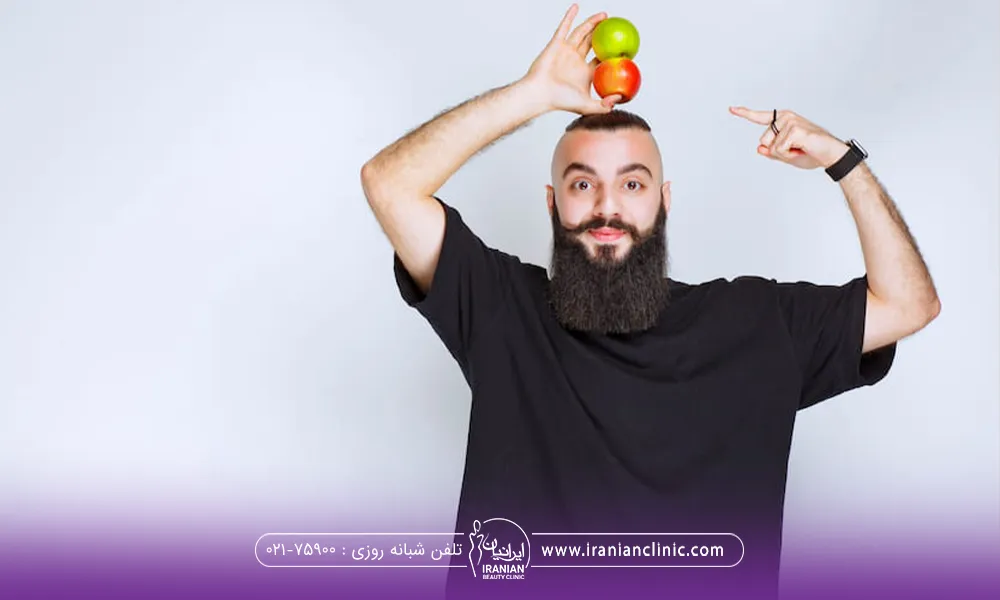 مردی که با یک دست دو عدد سیب را روی سرش به طوری ه سیب هاروی هم قرار گرفته است نگه داشته و با دست دیگر به سیب ها اشاره کرده است