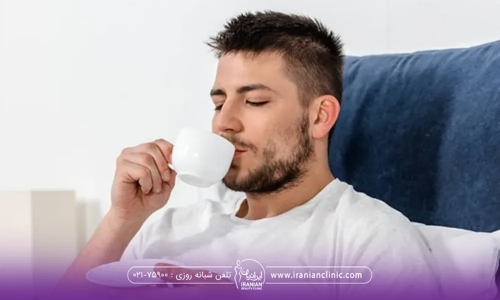 مردی که روی تخت خواب نشسته است و چشم هایش را بسته و در حال نوشیدن قهوه است - خوردن قهوه بعد از کاشت مو