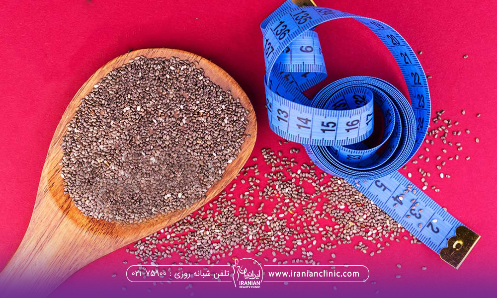 یک قاشق چوبی که حاوی دانه چیا است و کمی از دانه روی زمین کنار قاشق ریخته شده و یک متر آبی رنگ